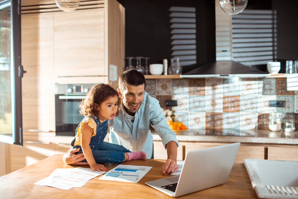 Man and daughter viewing laptop in kitchen
