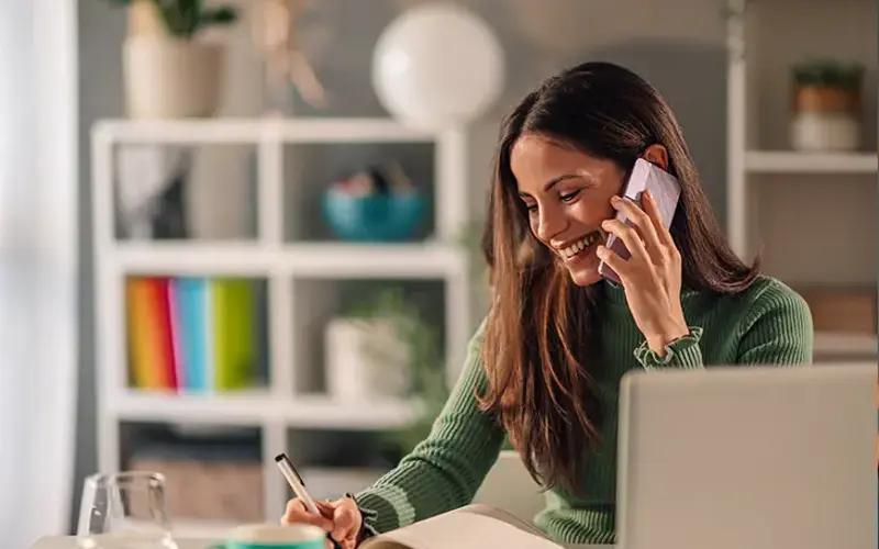 Woman on phone writing in notebook