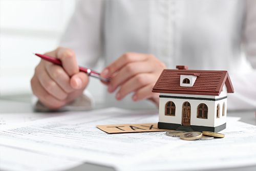 figurine house and tax sign on stack of papers