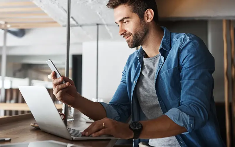 Man in coffee shop, laptop and smartphone, small business