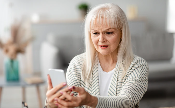 older woman upset by what she sees on her mobile phone