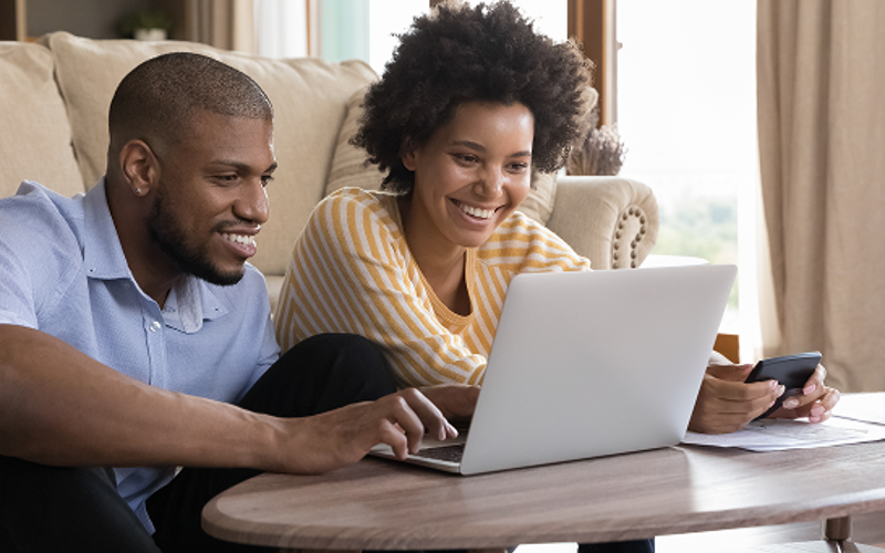 Happy couple engaged with laptop and digital devices
