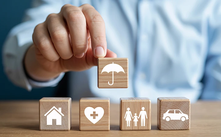 blocks displaying various insurance needs with an umbrella covering them