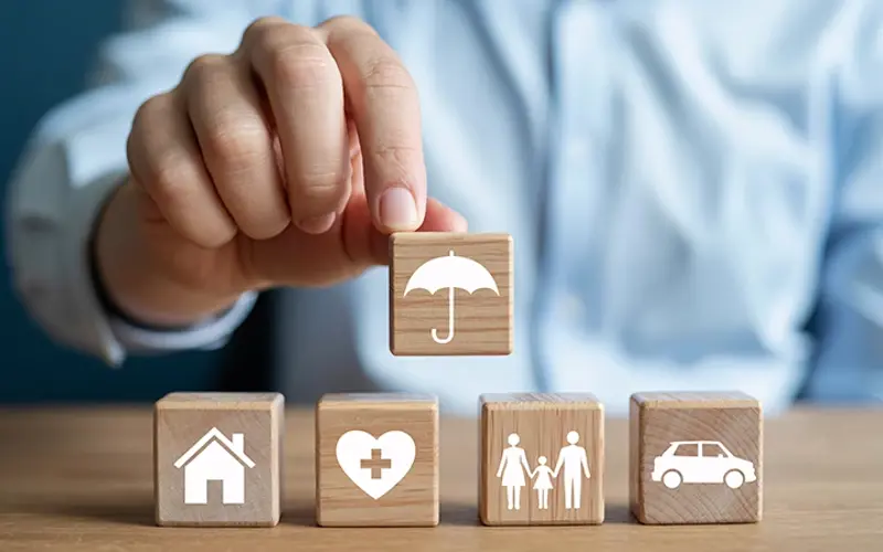 blocks displaying various insurance needs with an umbrella covering them