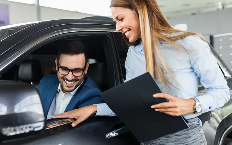 Saleswoman at the dealership showroom talking with customer 