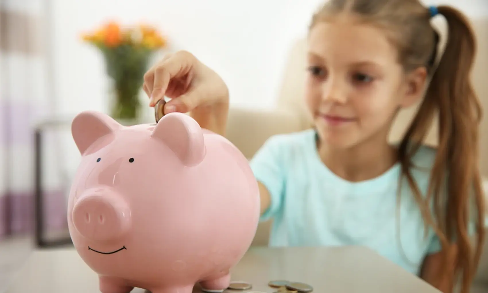 Girl putting money into a piggy bank