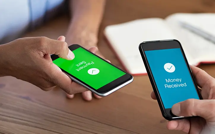 people holding phones as they send and receive money from each other
