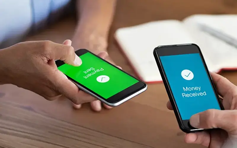people holding phones as they send and receive money from each other
