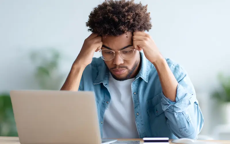 worried looking man staring at laptop screen