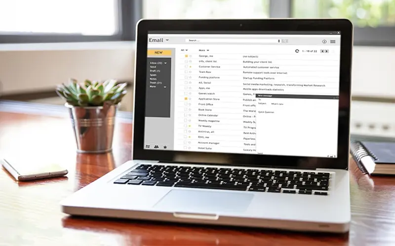 laptop on desk showing email application 