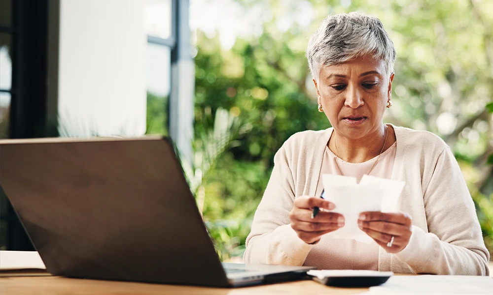 older woman reviewing receipts next to a calculator