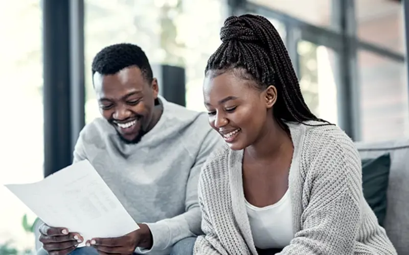 Man and woman sitting on a couch signing paper work