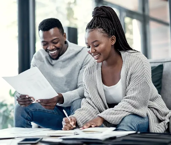Man and woman sitting on a couch signing paper work