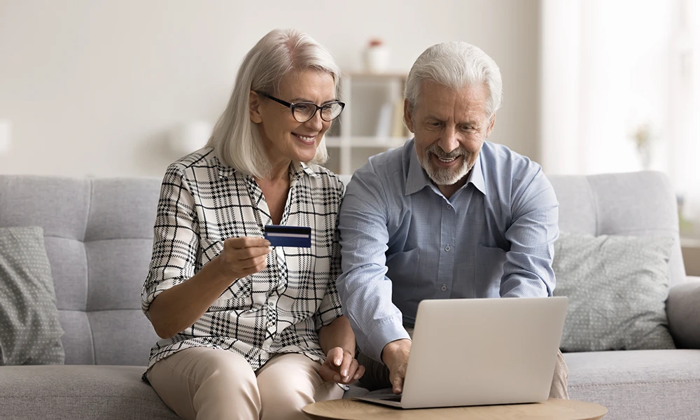 happy older couple buying something online with a credit card