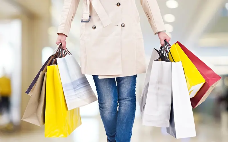 woman carrying many department store shopping bags