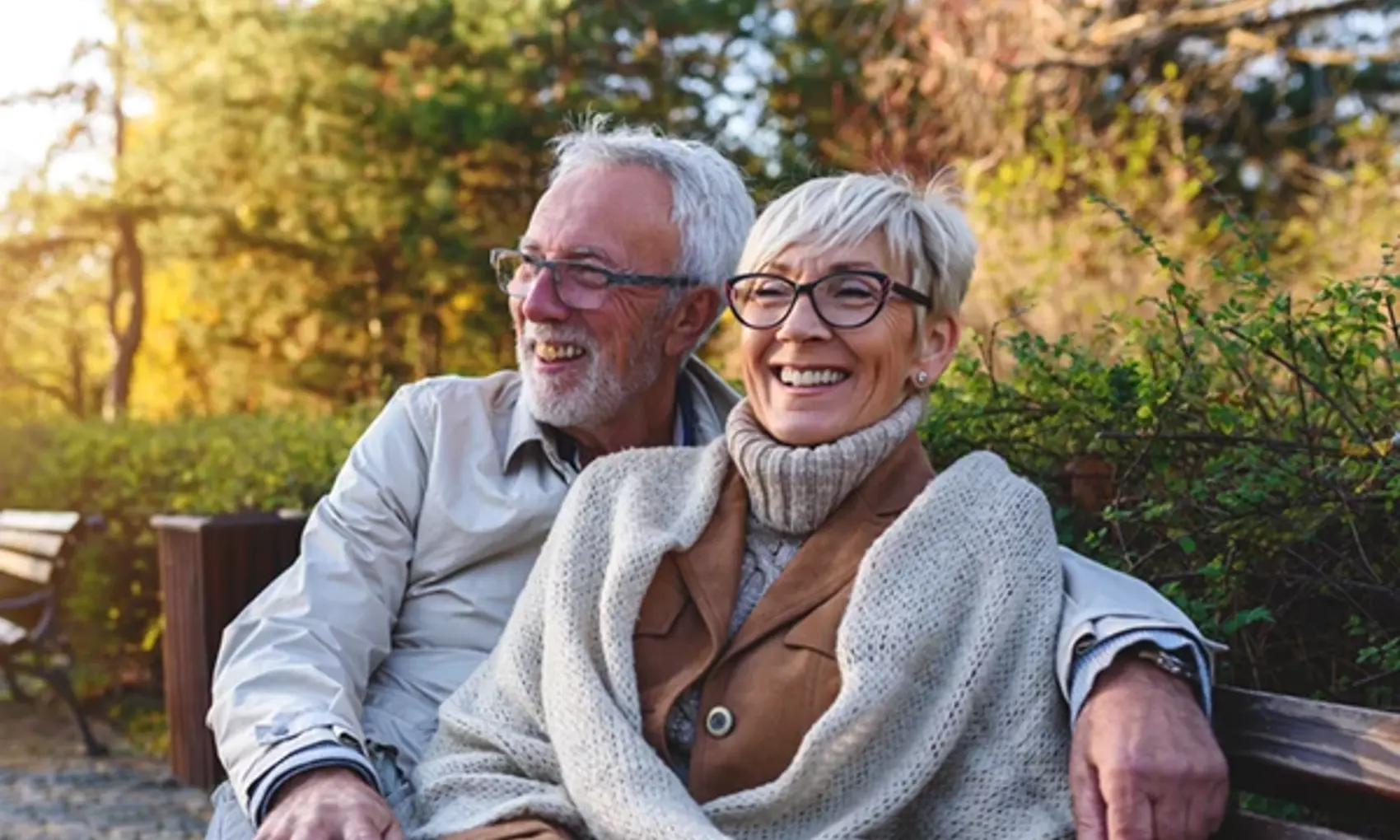 Smiling older couple sitting on bench outdoors