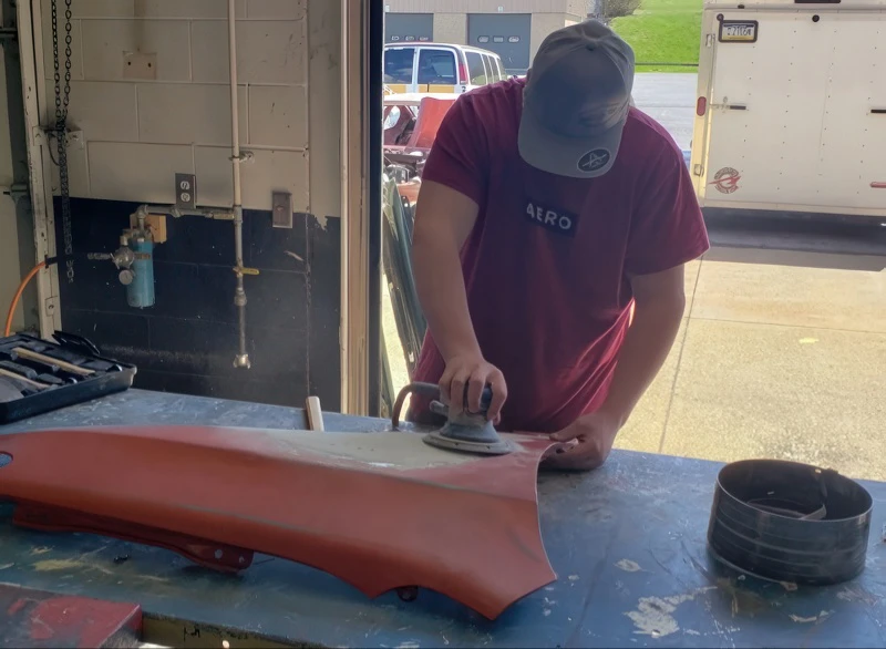 young man sanding a hood of a car