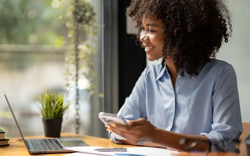 Woman using phone and laptop for finances