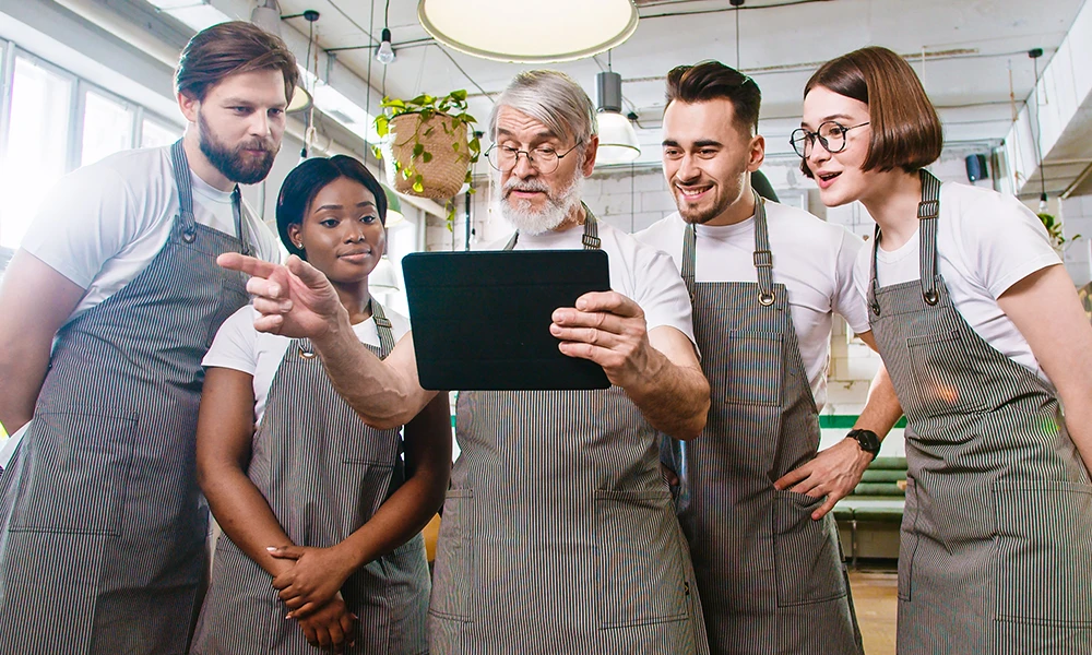 boss showing his pleased employees something on a tablet