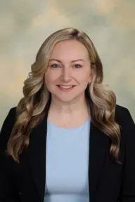 Portrait of Katie Rittel wearing a grey shirt with a black blazer.